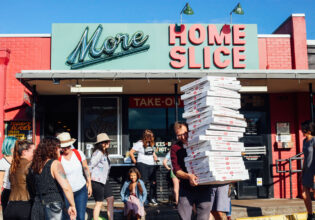a person holding boxes of pizza outside Home Slice pizzeria, South Congress Avenue