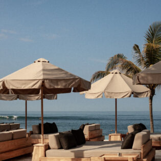 a beachfront club with umbrellas and sunbeds at The Lawn, Bali