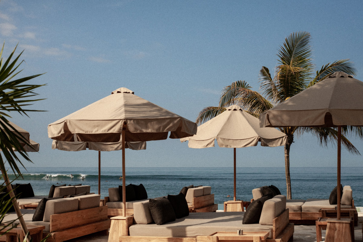 a beachfront club with umbrellas and sunbeds at The Lawn, Bali