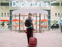 a young woman in front of the departures area at the airport