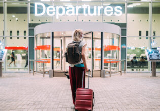 a young woman in front of the departures area at the airport