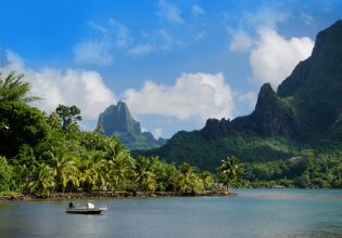 Mountains and ocean with boat in forefront on islands of Tahiti