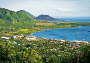 Rabaul with the dark cone of Mt Tavurvur on the horizon.